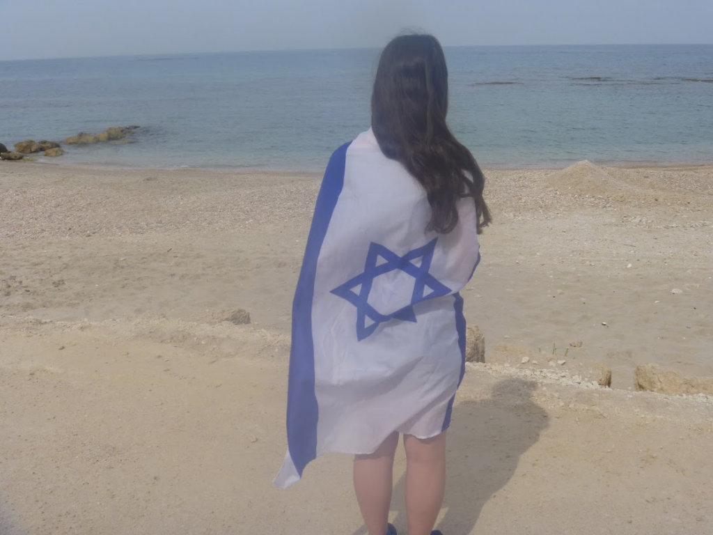 Jewish teen female with Israeli flag on beach in Israel Caesarea